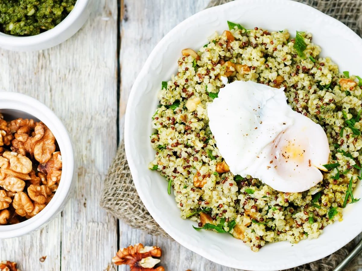 Ein weißer Teller mit Quinoa-Salat mit Bärlauch-Pesto.