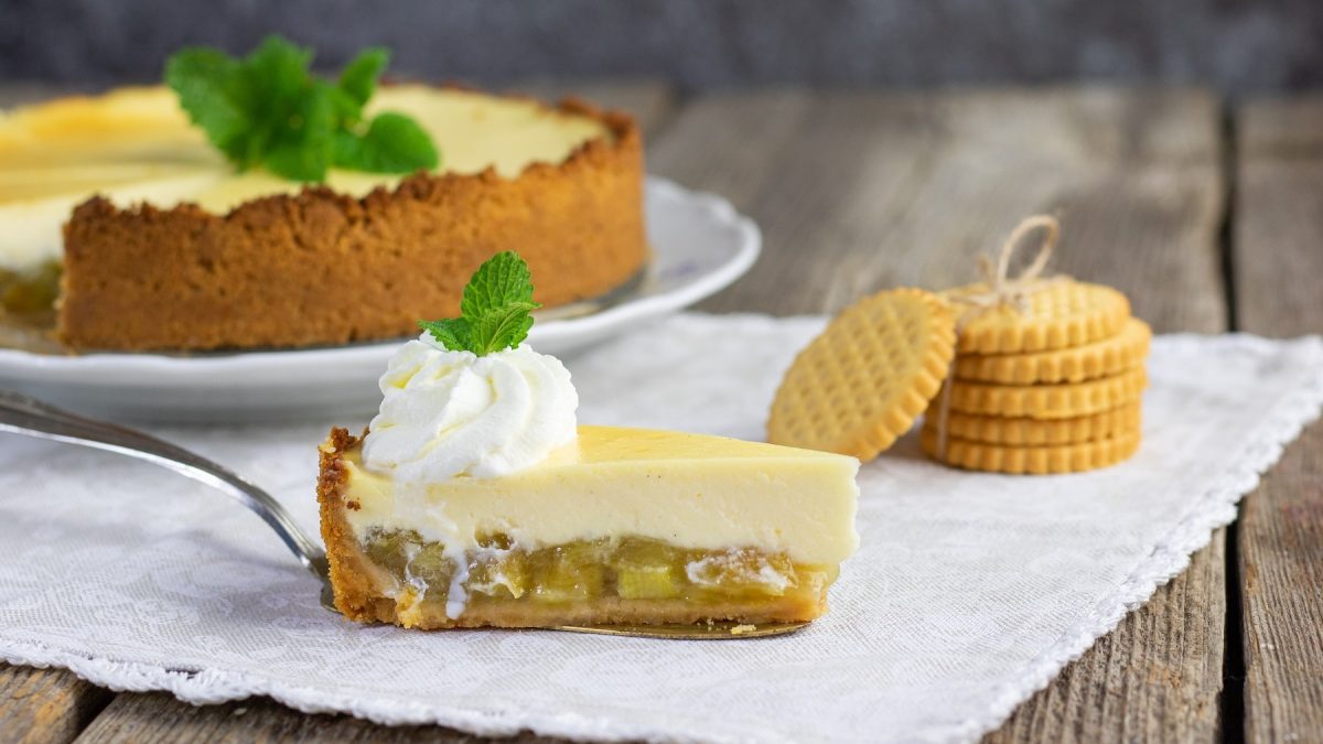 Ein Stück Rhabarber-Cheesecake auf einer Serviette mit Keksen.