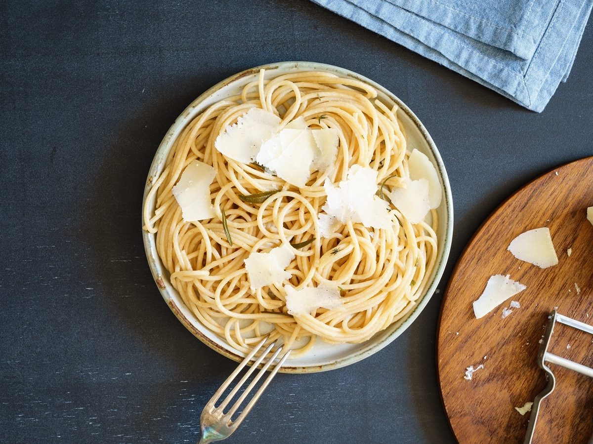 Ein Nudelteller mit Pasta mit Rosmarinbutter auf einem dunkelblauen Hintergrund.