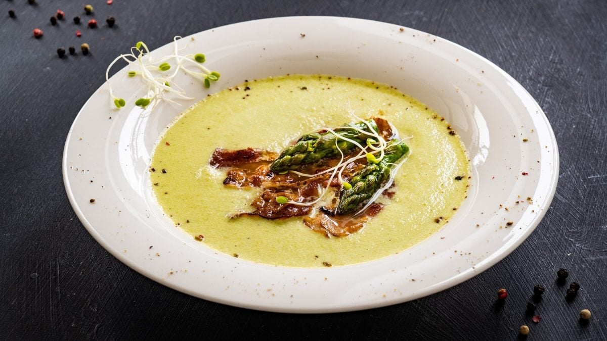 Ein weißer Teller mit der Spargel-Kartoffelcremesuppe auf dunklem Untergrund.