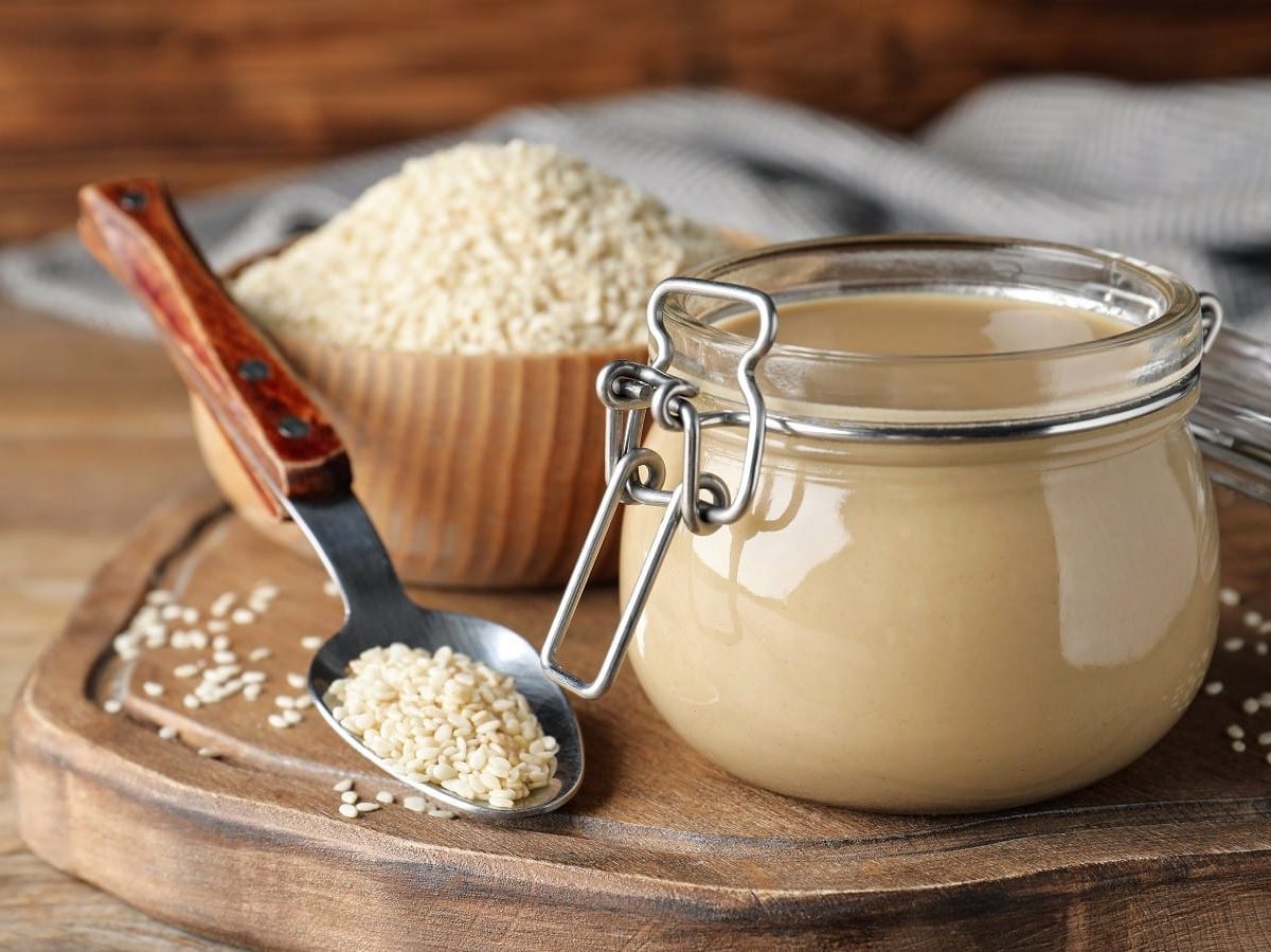 Ein Weckglas mit Tahini auf einem Holzbrett.