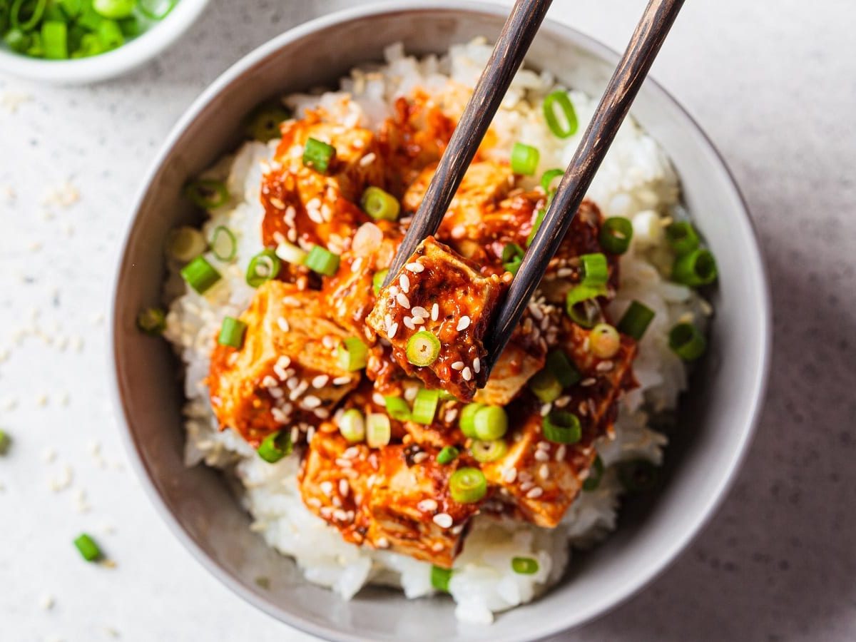 Ein Teller mit Tofu in Gochujang-Sauce auf einem hellen Tisch.