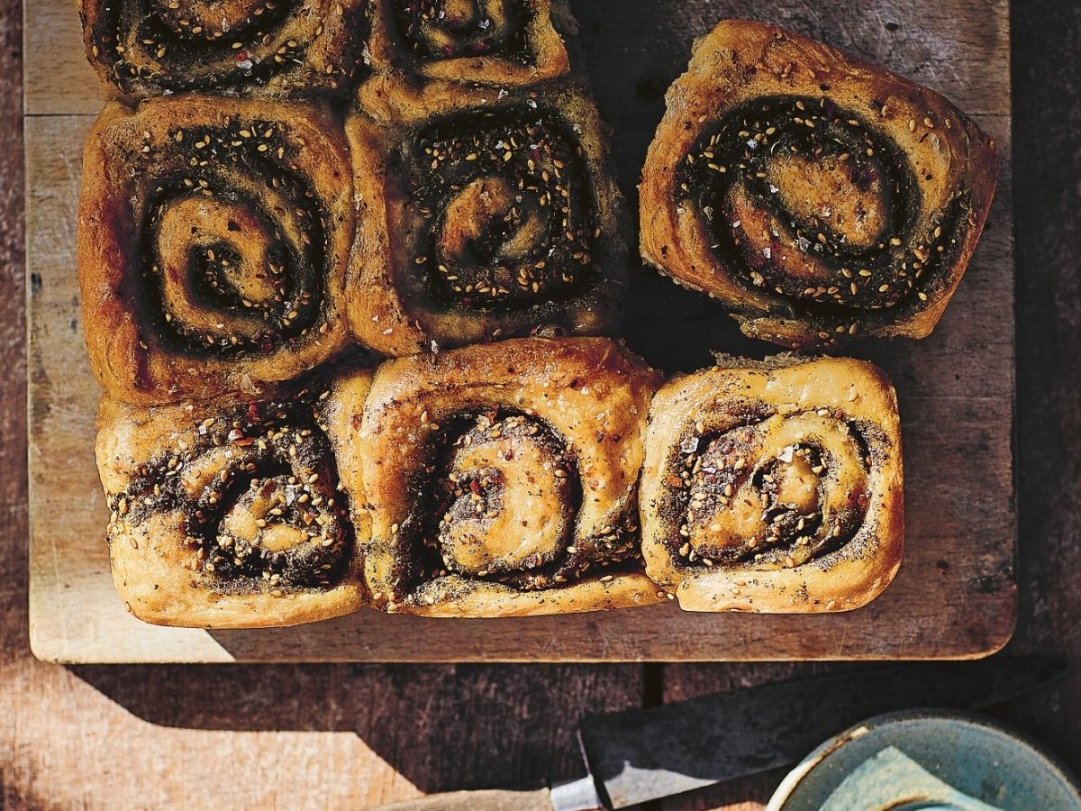 Ein Holzbrett mit mehreren herzhaften Za’atar-Schnecken in der Draufsicht.