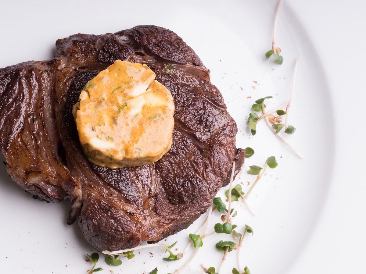 Ein weißer Teller mit einem Stück Steak und Café de Paris Butter.