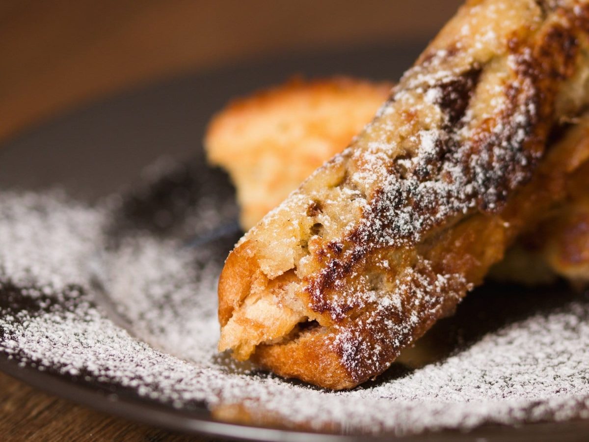 French-Toast-Röllchen mit Puderzucker bestreut auf einem Teller.