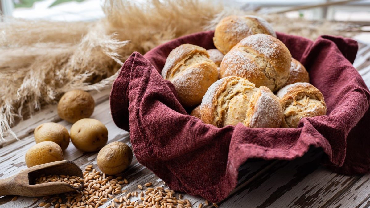 Selbst gemachte Kartoffelbrötchen in einem Brotkorb. Im Bild Kartoffeln, Kerne und Weizen. Frontalansicht.