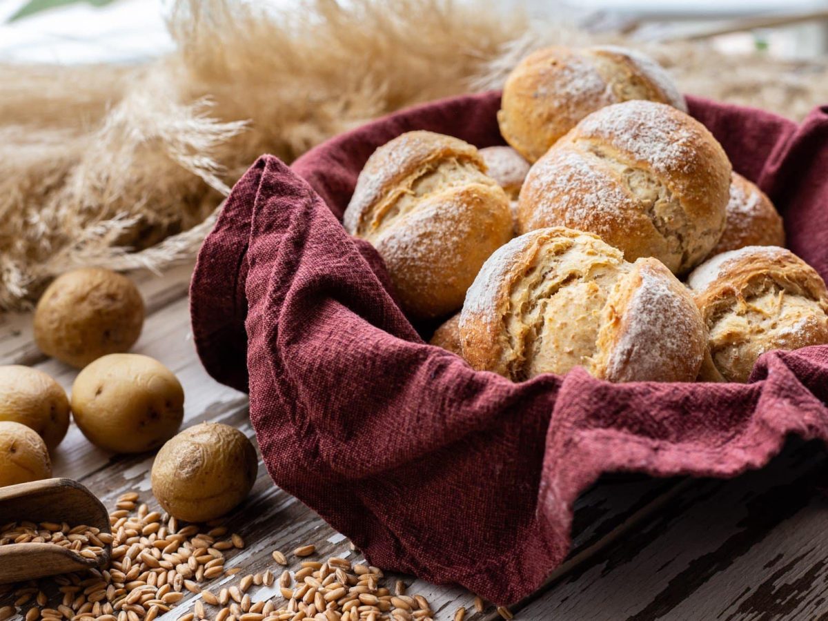 Selbst gemachte Kartoffelbrötchen in einem Brotkorb. Im Bild Kartoffeln, Kerne und Weizen. Frontalansicht.