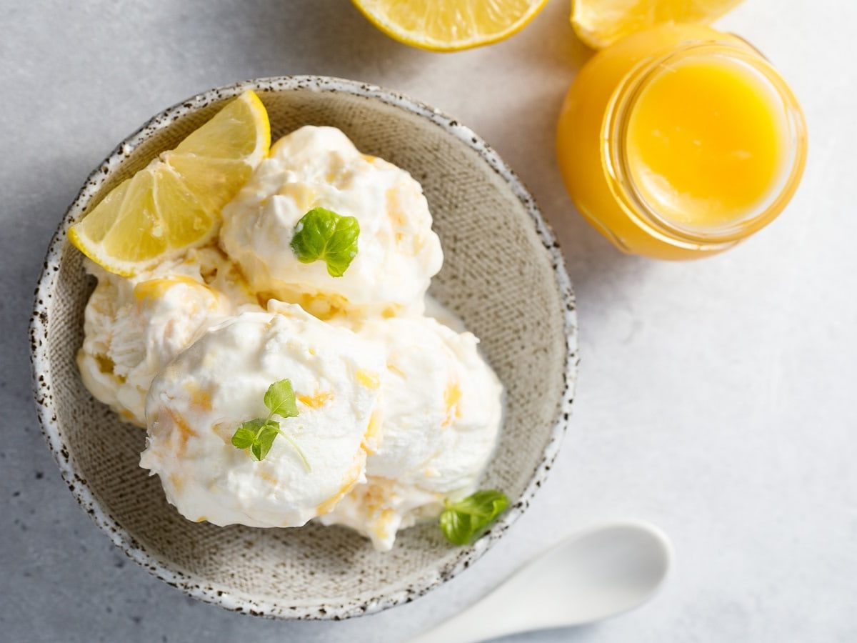 Ein Becher mit Lemon Curd Eis auf einem weißen Tisch.