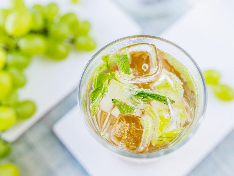 Ein Glas Lillet Elite auf hellem Untergrund mit Weintrauben direkt von oben fotografiert,