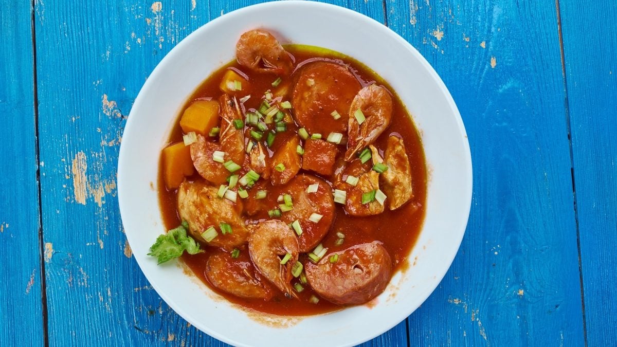 Ein weißer Suppenteller mit der Louisana-Soup auf einem blauen Holztisch.