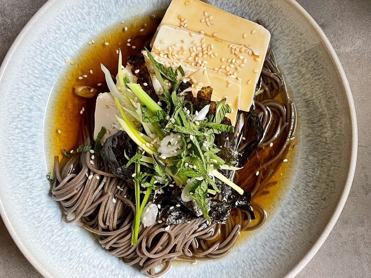 Ein Teller mit Memil Guksu auf einem grauen Hintergrund.