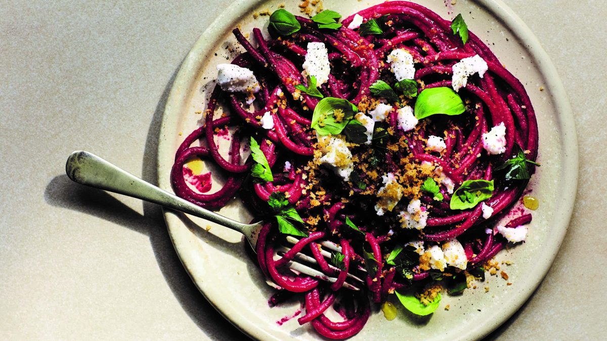 Rote-Bete-Bucatini mit Knoblauchbröseln, Basilikum und Feta auf einem Teller in der Draufsicht, darauf auch eine Gabel.