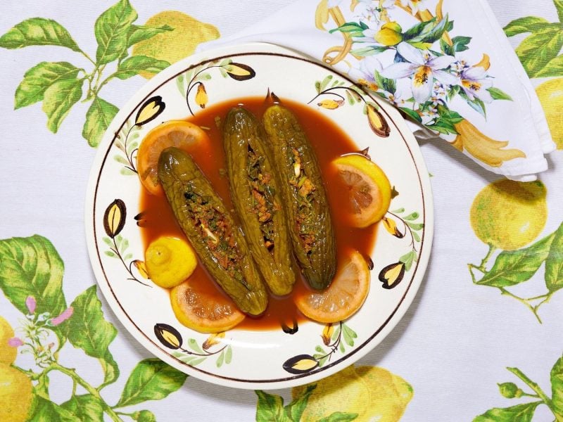 Drei gefüllte eingelegte Salatgurken, auch als Torshi Mahschie bekannt, auf einem Teller mit roter Sauce, Draufsicht.