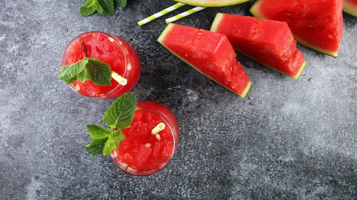 Zwei Gläser mit Wassermelonen-Minze-Smoothie auf einem grauen Tisch.