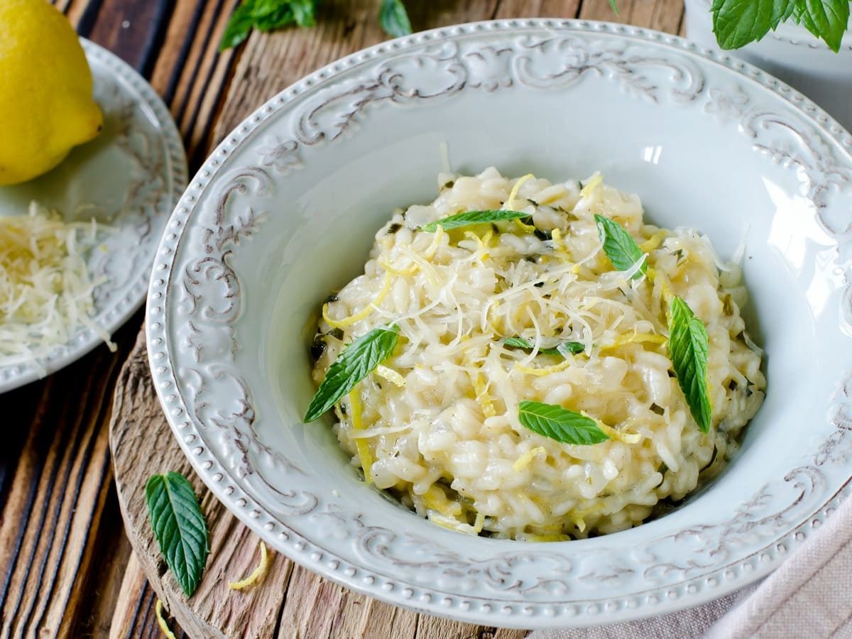 Ein Teller mit Zitronen-Risotto mit Minze auf einem Holztisch.