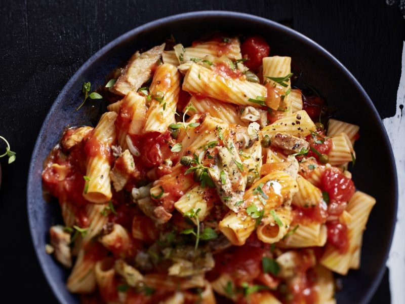 Eine dunkelblaue Bowl mit Pasta von oben fotografiert vor einem schwarz/weißen Hintergrund.