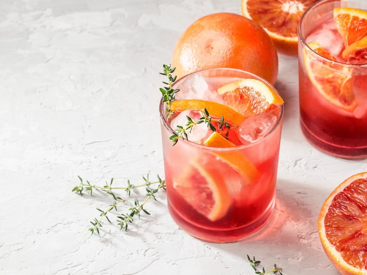 Ein Glas mit Campari Spritz auf einem hellen Hintergrund.