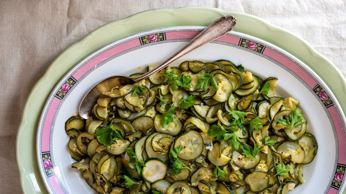 Ein Teller geschmorte Zucchini mit Zimt, Sardellen und Knoblauch, darin ein Löffel.