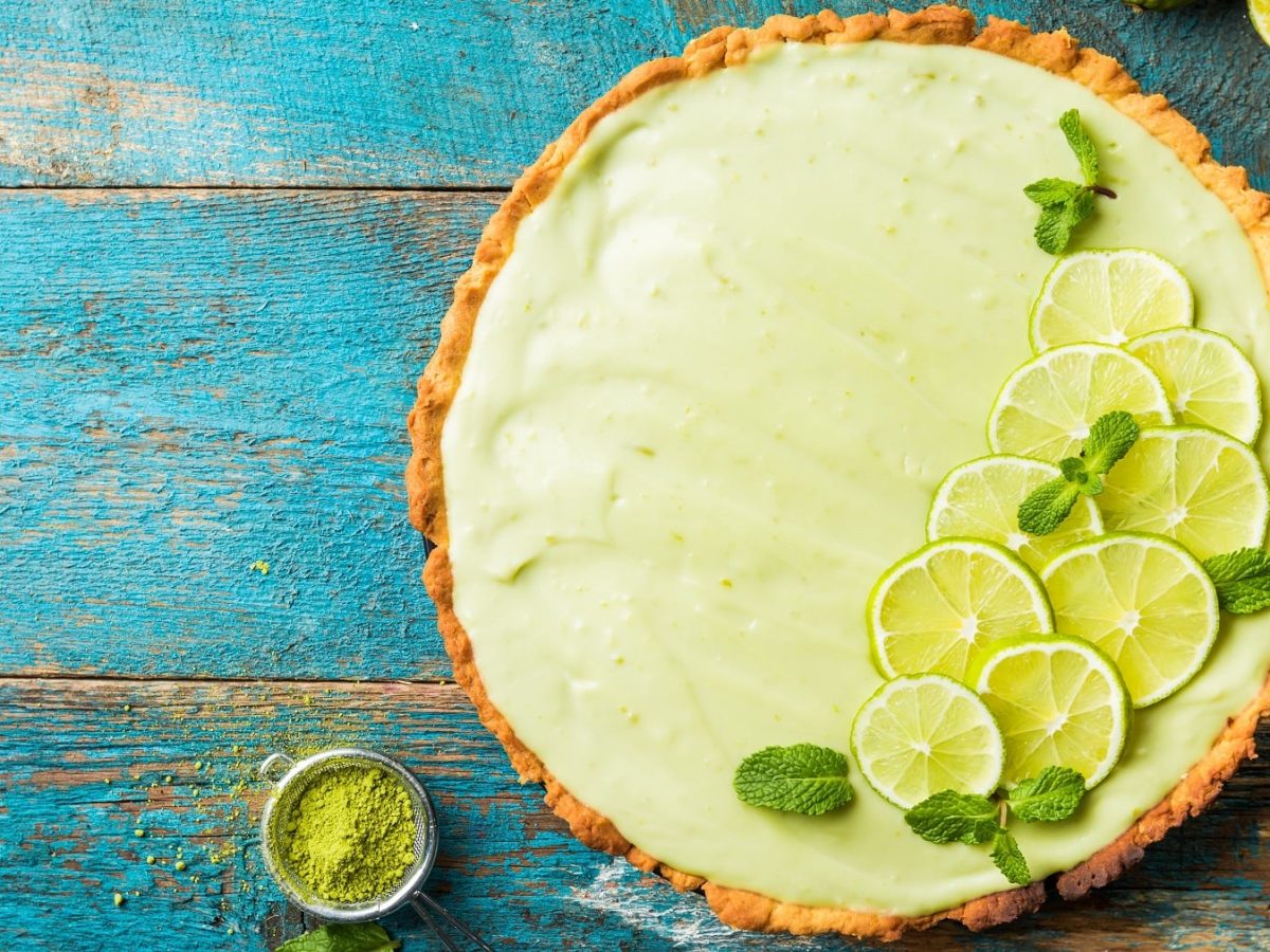 Ein Key Lime Pie mit Matcha auf einem rustikalen Holztisch, der leicht blau lackiert ist.