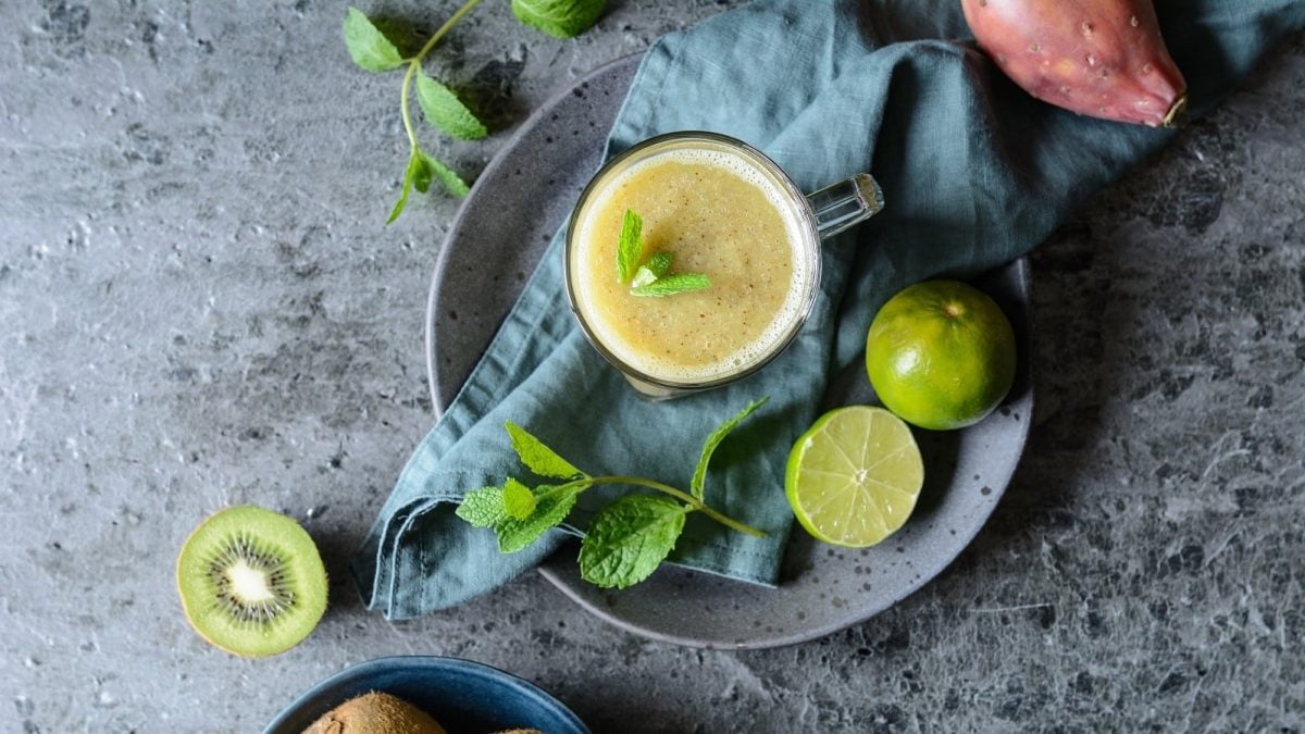 Ein Glas Kiwi-Smoothie auf einem grauen Tisch.