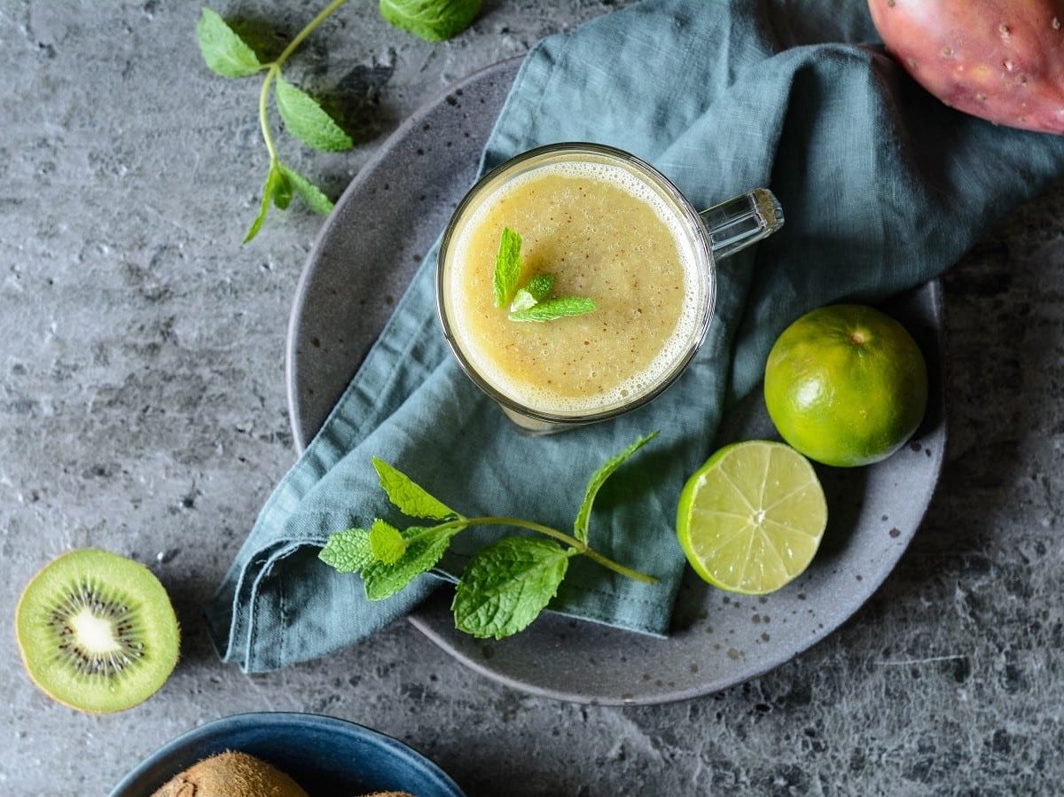 Ein Glas Kiwi-Smoothie auf einem grauen Tisch.