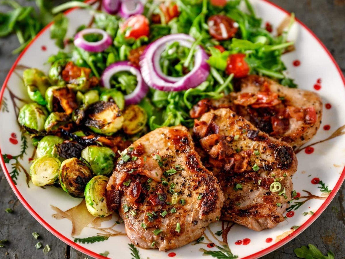 Selbst gemachte Minutensteaks nach Gyros-Art vom Grill drei gegrillte Minutensteaks Gyros mit Salat und Rosenkohl auf Teller auf dunklem Holz. Draufsicht.