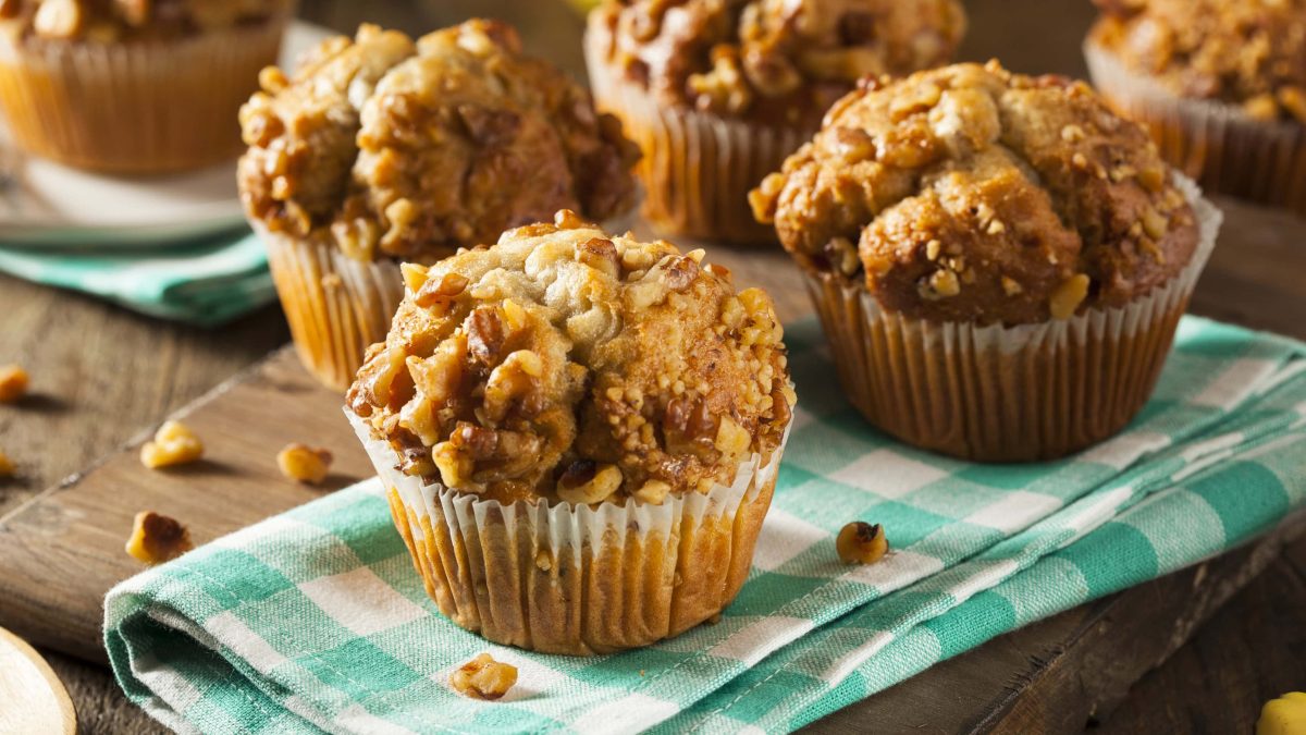 Mehrere Muffins auf einem dunklen Holztisch mit grün-weiß-karierter Tischdecke.