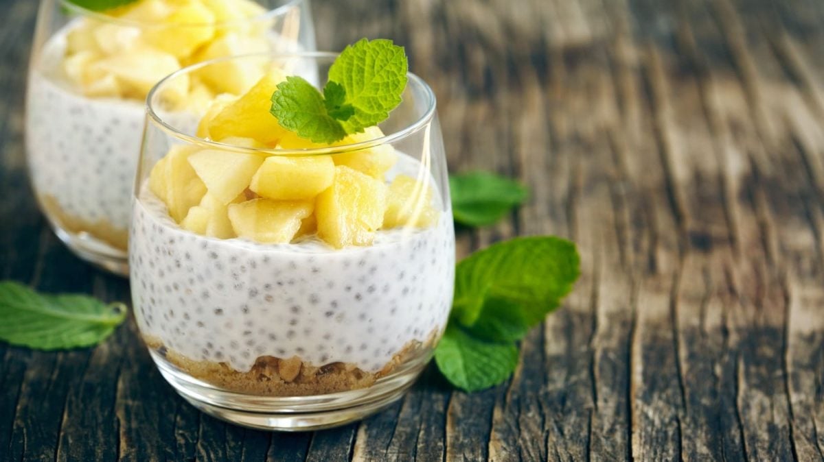 Ein Glas mit Piña Colada Overnight Oats auf einem Holztisch.