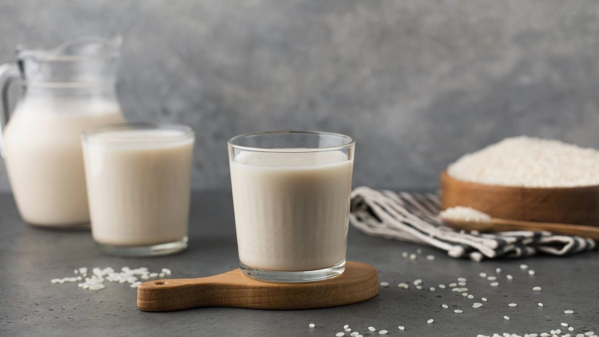 Zwei Gläser mit Reismilch auf einem Holztablett.