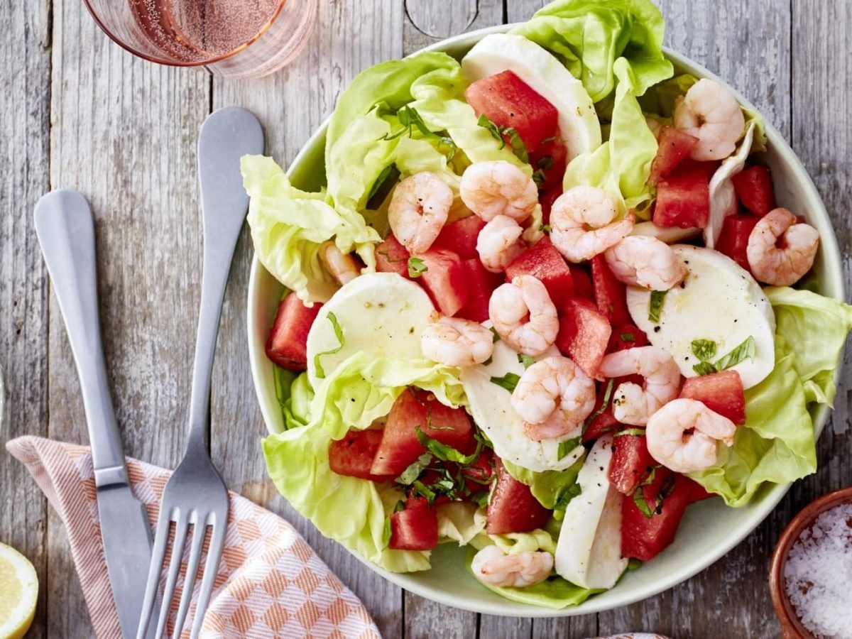 In einer Schüssel ist ein Wassermelonen-Salat mit Mozzarella angerichtet. Er ist mit Garnelen verfeinert.