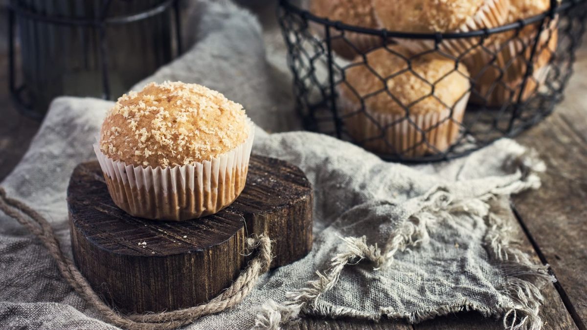 Ein Kokos-Muffin auf einer Holzscheibe.