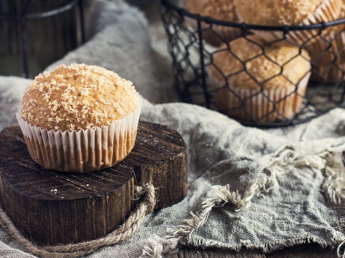 Ein Kokos-Muffin auf einer Holzscheibe.