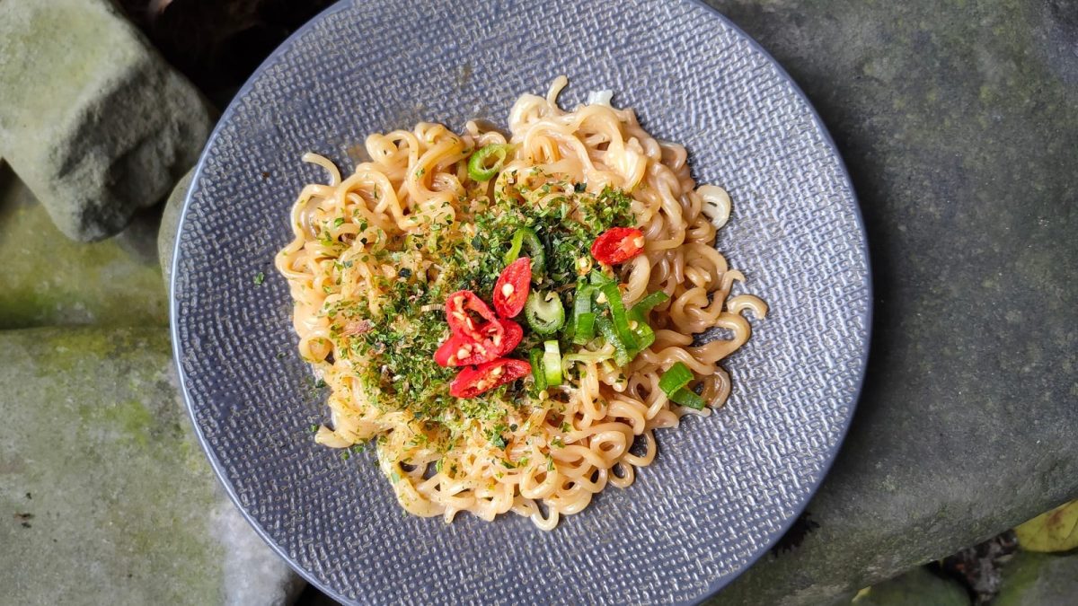 Ein Teller mit Chili Cheese Ramen und einem Stein-Untergrund.