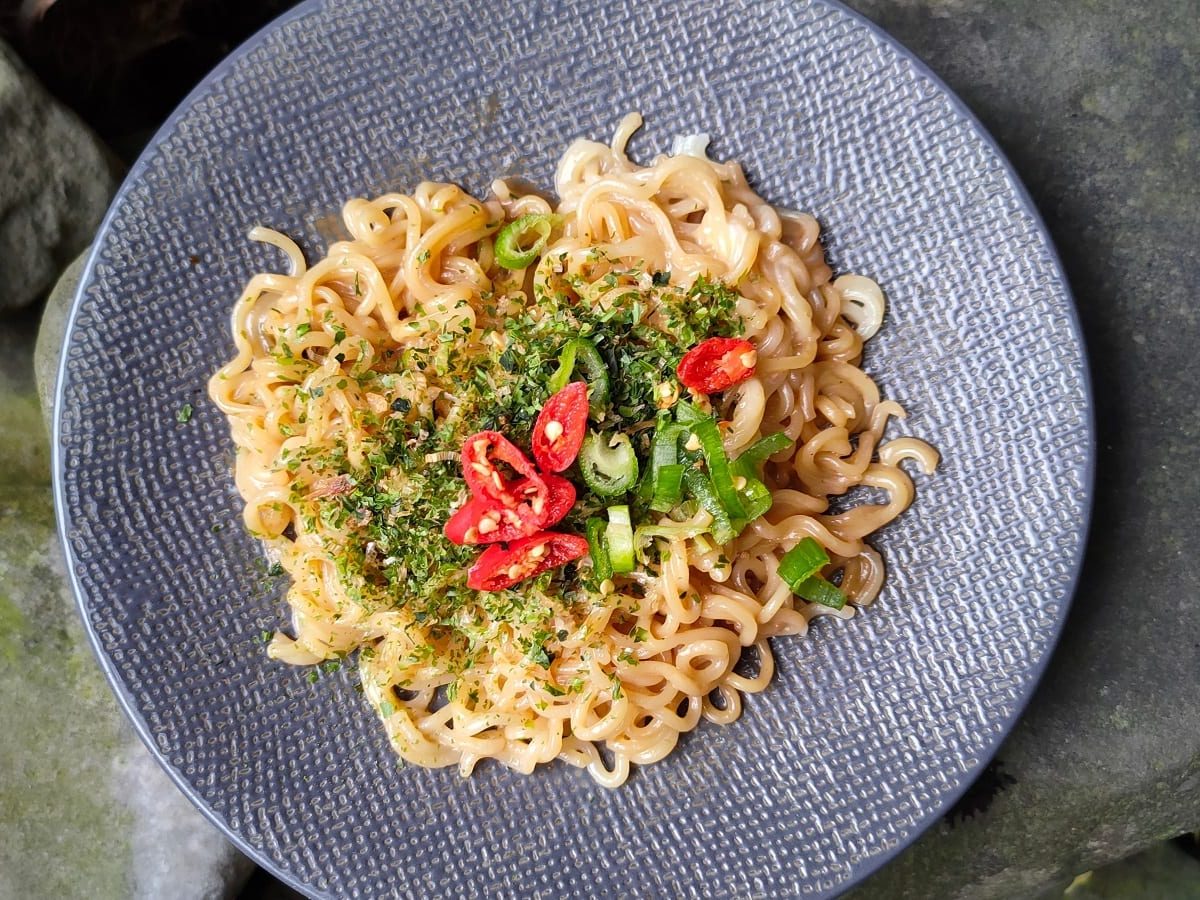 Ein Teller mit Chili Cheese Ramen und einem Stein-Untergrund.