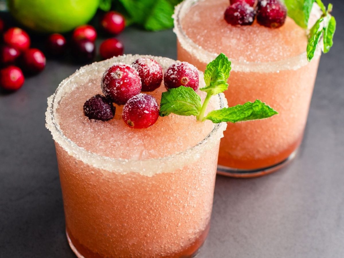 Draufsicht: zwei Frozen Cranberry Margarita. Im Bild Cranberrys, Minze und Limetten.