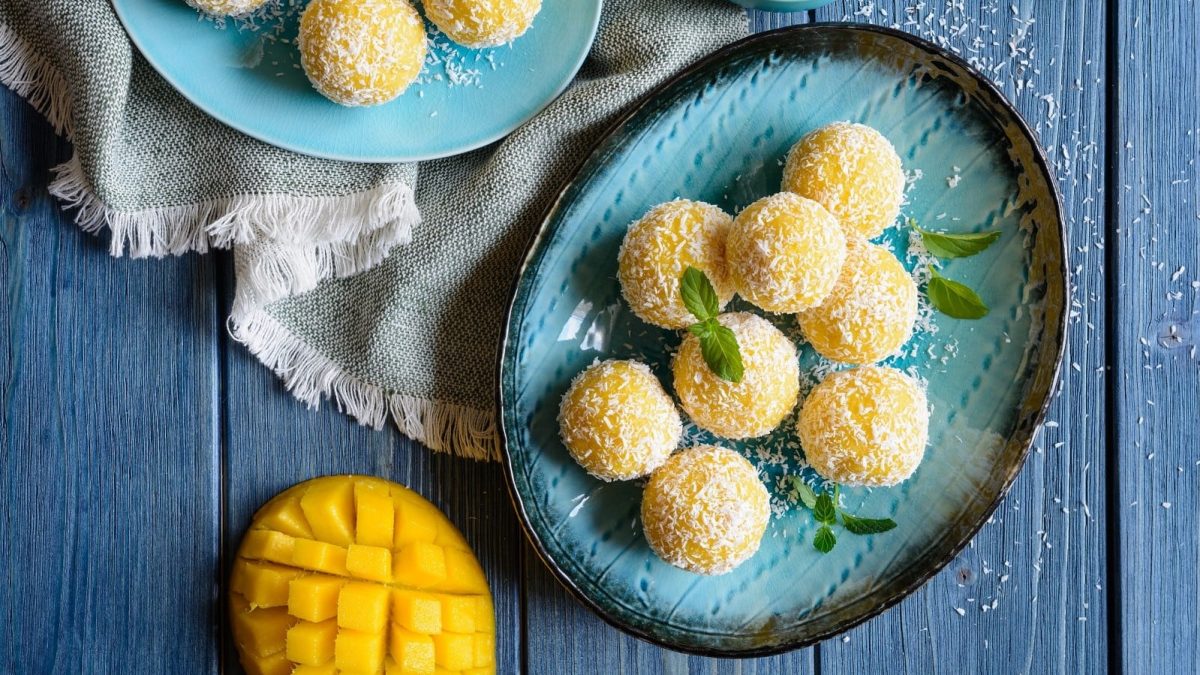 Zwei Portionen Mango Ladoo auf einem ovalen Teller auf einem blauen Holztisch.