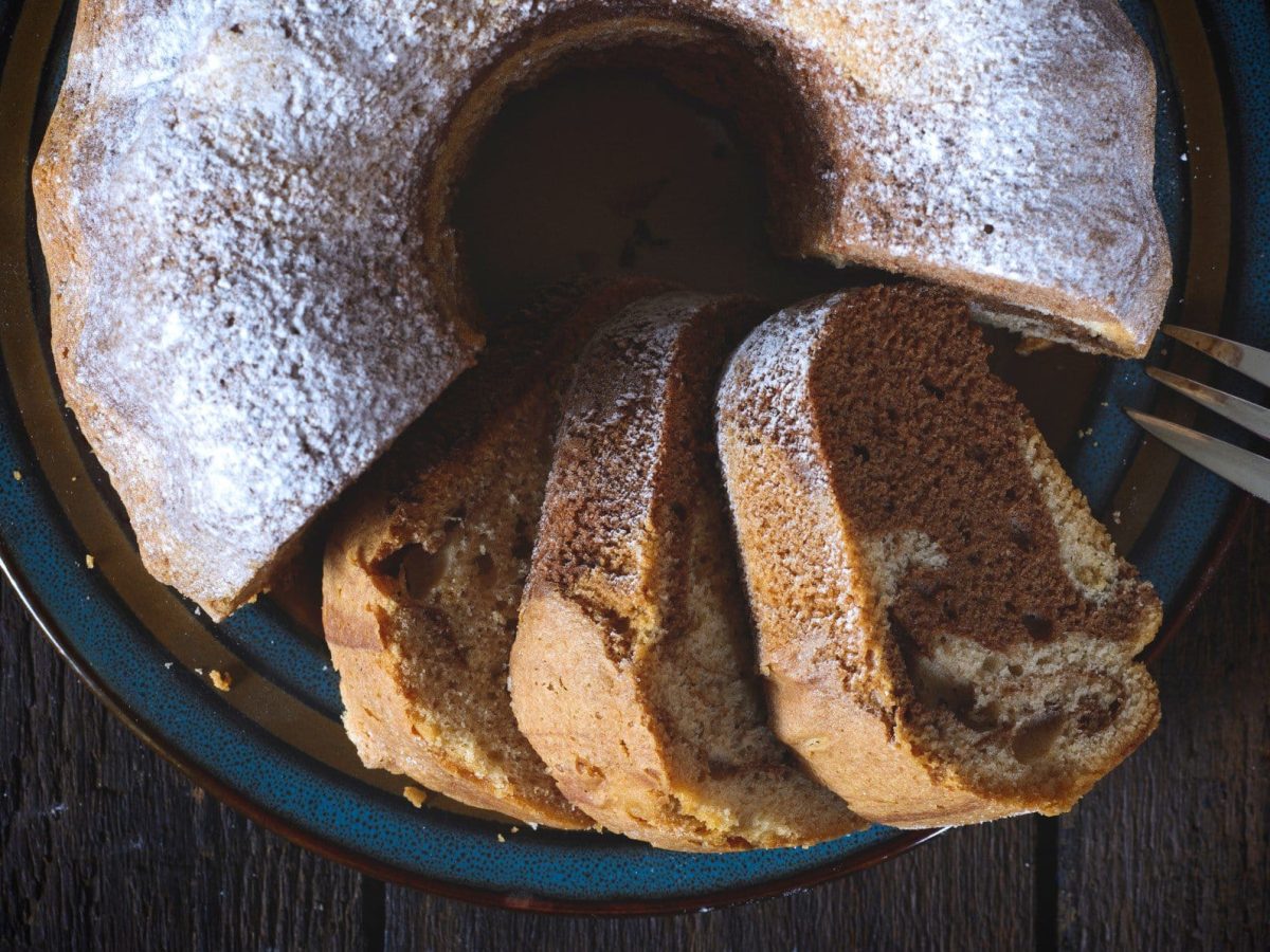 Marmor-Schüttelkuchen mit Puderzucker von oben auf dunklem Holz.