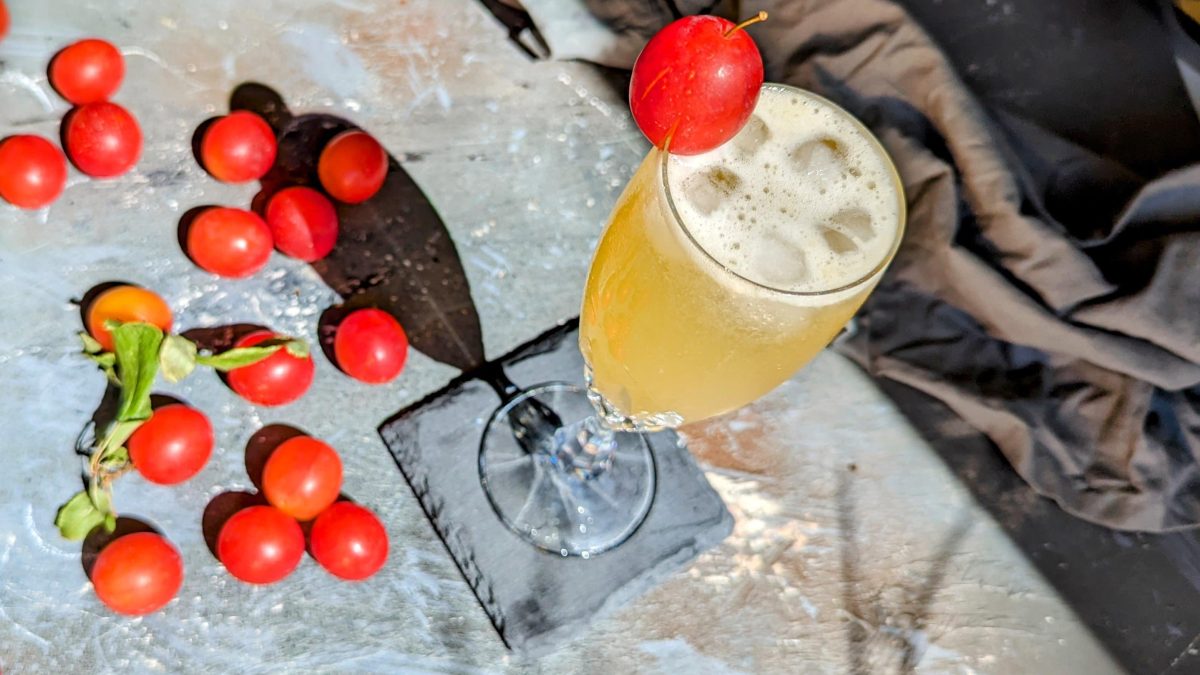 Das Mira-Bellini Glas auf einem Schiefer-Coaster udn grauem Tisch mit Mirabellen und grauer Tischdecke.