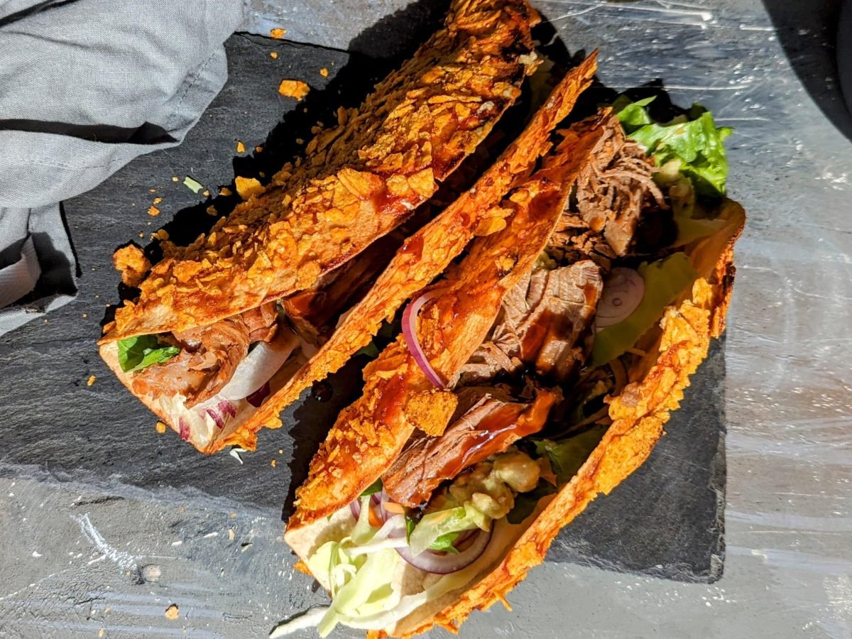 Zwei Nacho-Wraps auf einer Schieferplatte mit grauem Tisch und grauer Tischdecke.