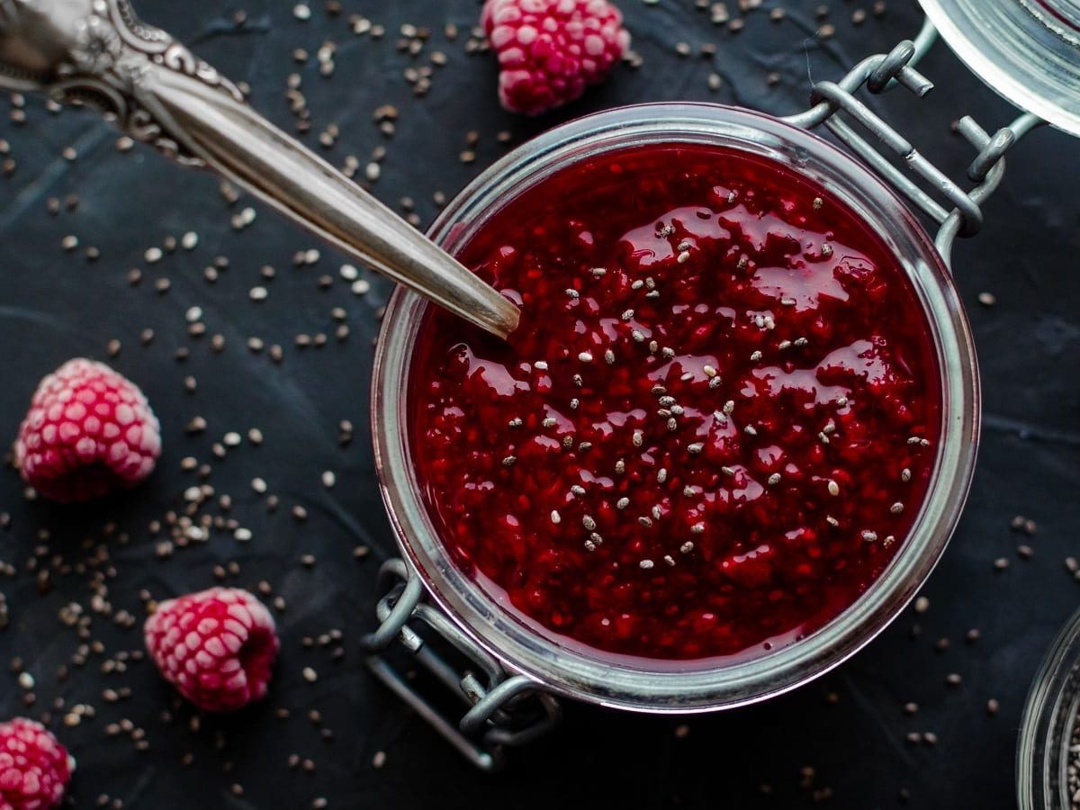 Ein Weckglas mit Himbeer-Chia-Marmelade auf einem dunklen Untergrund.