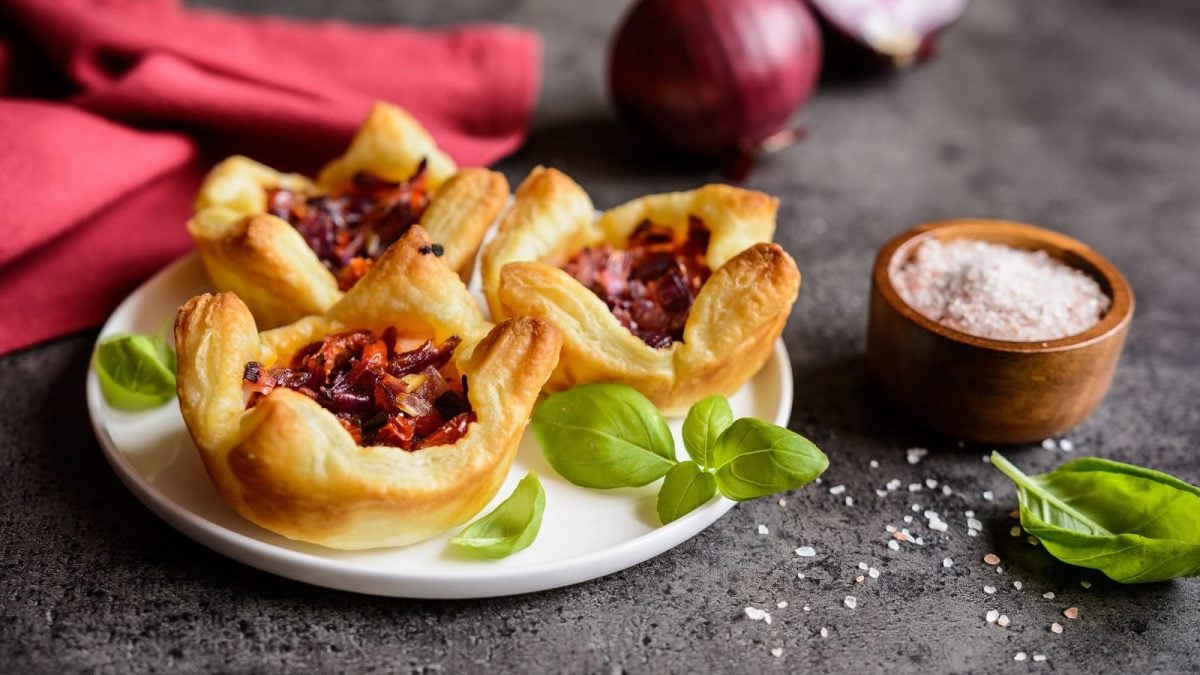 Ein Teller mit Blätterteig-Muffins mit getrockneten Tomaten darauf.