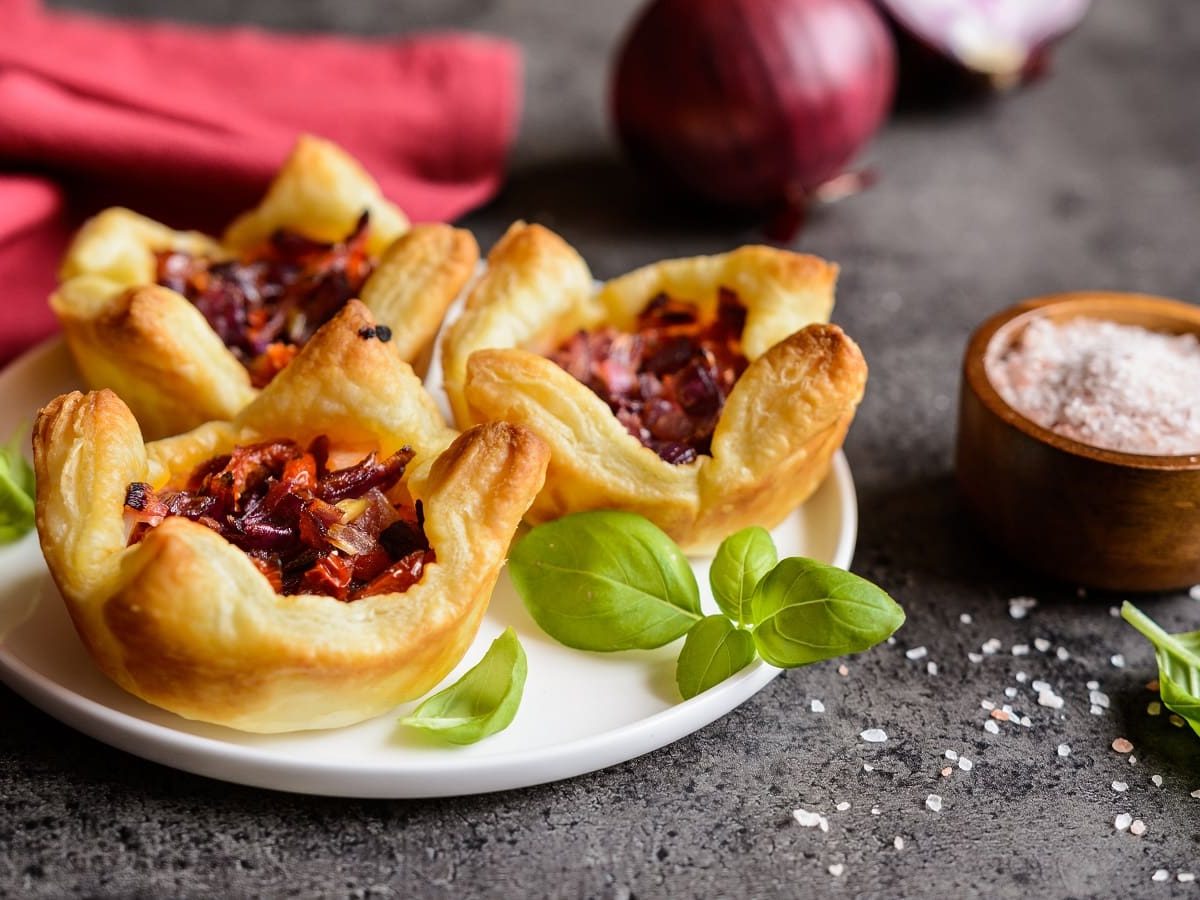 Ein Teller mit Blätterteig-Muffins mit getrockneten Tomaten darauf.