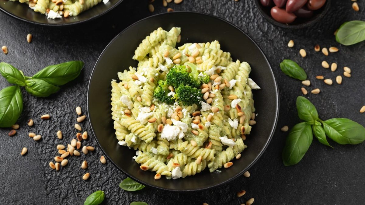 Ein schwarzer tiefer Teller mit Pasta mit Brokkoli-Feta-Sauce auf einem dunklen Untergrund.