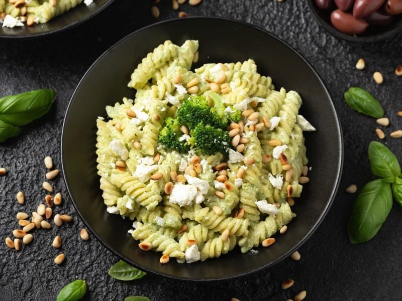 Ein schwarzer tiefer Teller mit Pasta mit Brokkoli-Feta-Sauce auf einem dunklen Untergrund.