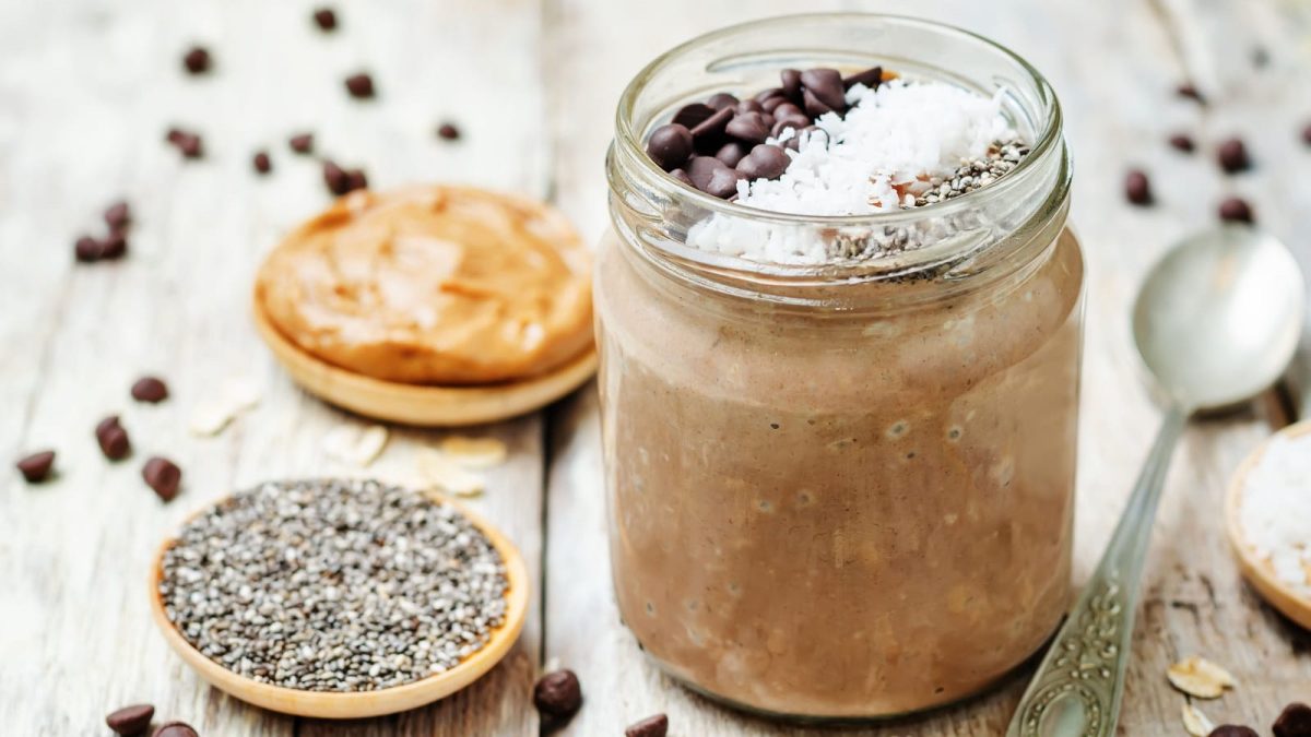 Ein Weckglas mit Cookie Dough Overnight Oats auf einem hellen Holztisch.