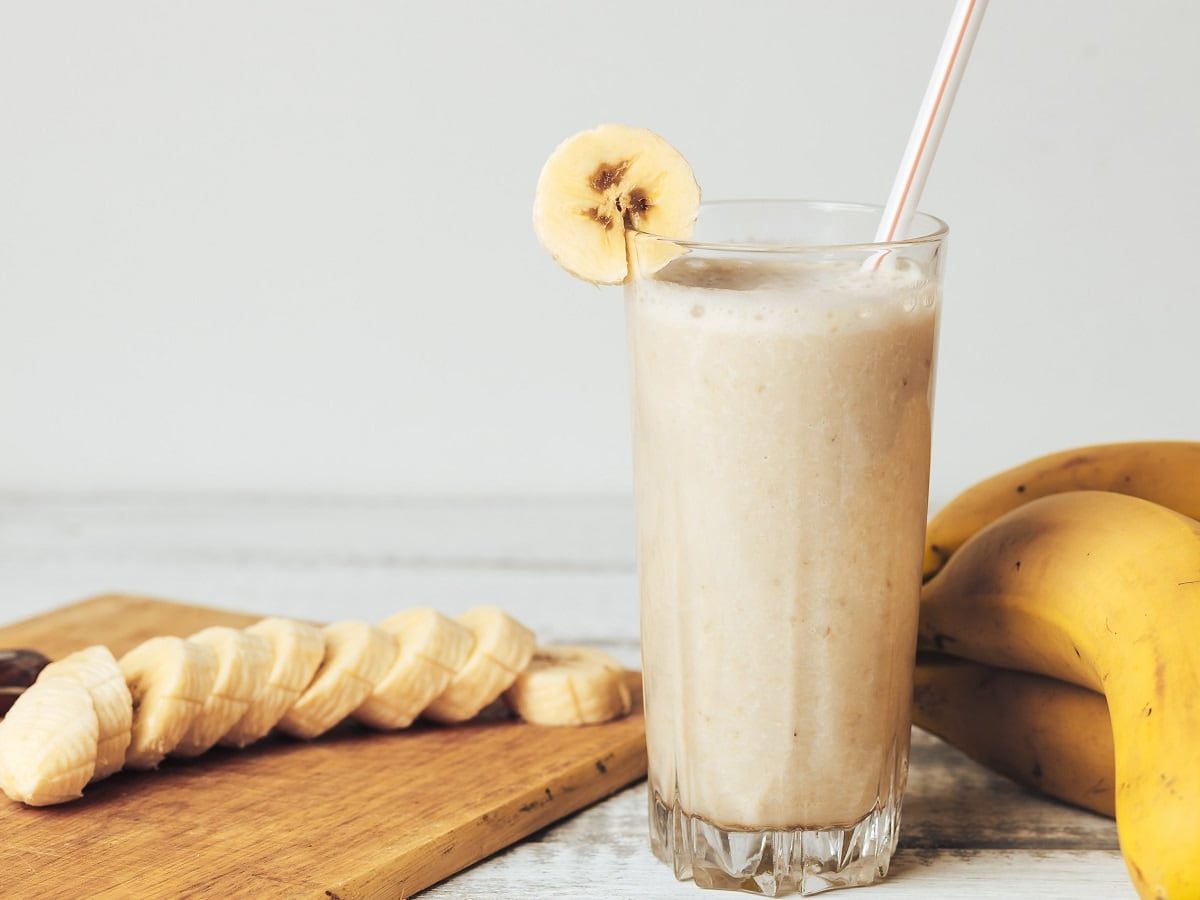 Ein Glas mit koreanischer Bananenmilch neben frischen Bananen.