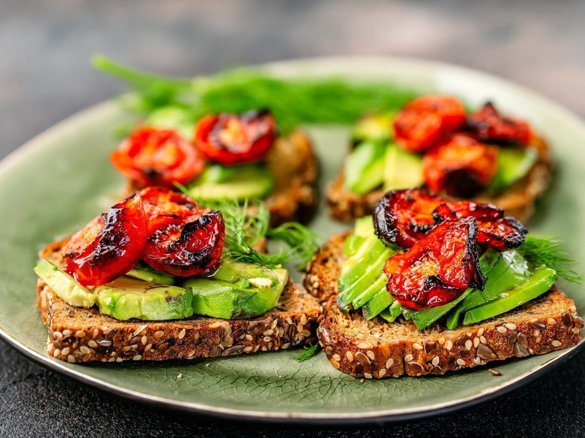 Ein Teller mit 4 Avocado-Stullen mit Rösttomaten