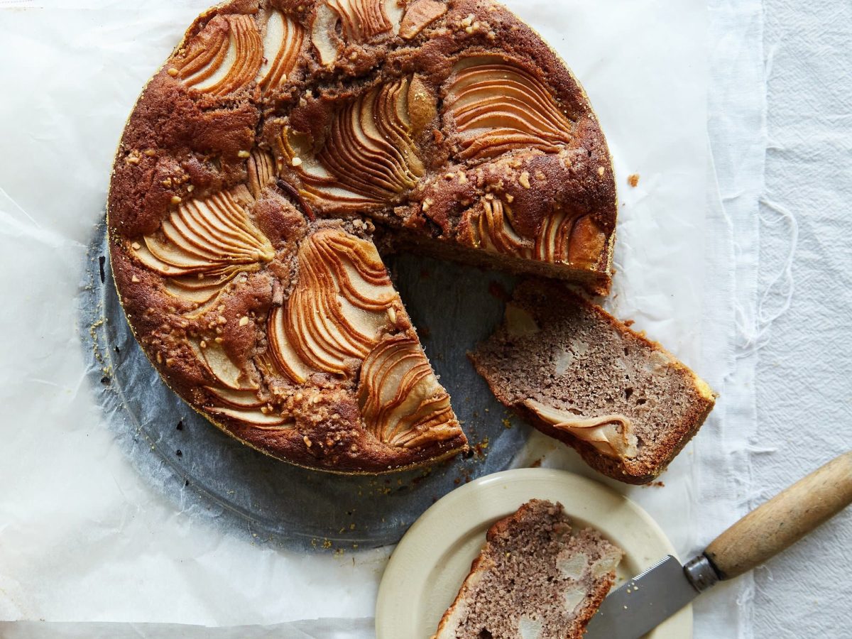 Ein Birnen-Haselnuss-Kuchen in der Draufsicht, ein Stück ist herausgeschnitten, das Rezept stammt aus dem Backbuch "Naschmittag".