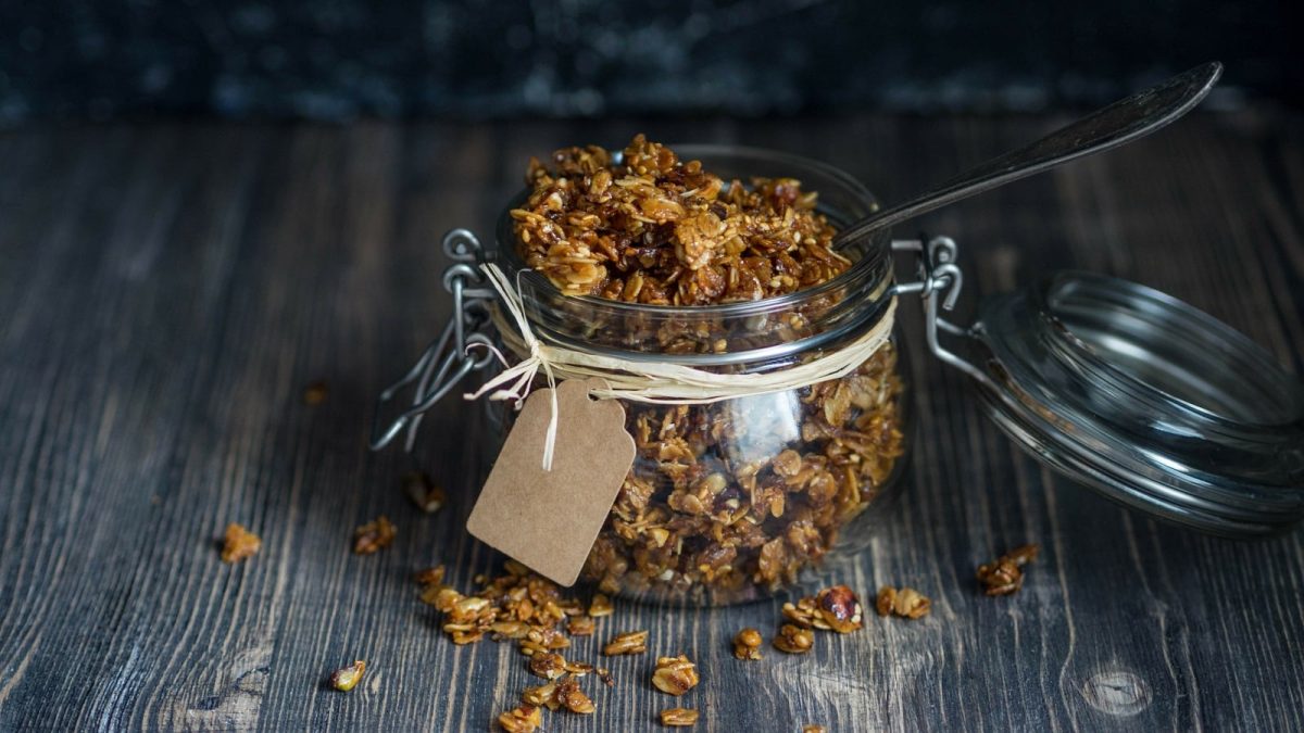 Ein Schraubglas mit Biscoff Granola auf einem Holztisch.