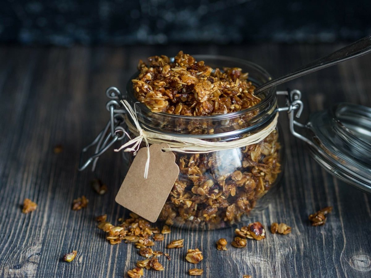 Ein Schraubglas mit Biscoff Granola auf einem Holztisch.